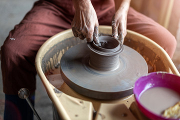 Hand made ceramics are formed by a mature woman on a potters wheel