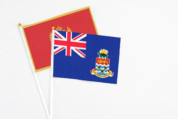 Fototapeta premium Cayman Islands and Montenegro stick flags on white background. High quality fabric, miniature national flag. Peaceful global concept.White floor for copy space.