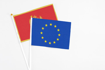 European Union and Montenegro stick flags on white background. High quality fabric, miniature national flag. Peaceful global concept.White floor for copy space.