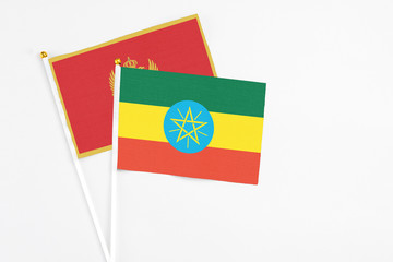 Ethiopia and Montenegro stick flags on white background. High quality fabric, miniature national flag. Peaceful global concept.White floor for copy space.