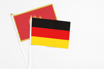 Germany and Montenegro stick flags on white background. High quality fabric, miniature national flag. Peaceful global concept.White floor for copy space.