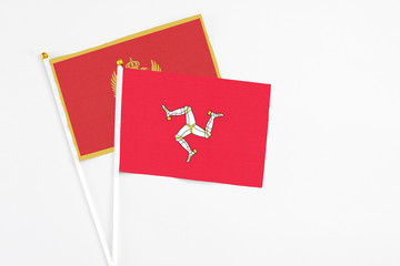 Isle Of Man and Montenegro stick flags on white background. High quality fabric, miniature national flag. Peaceful global concept.White floor for copy space.