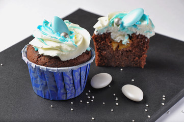 Chocolate cupcakes with blue cream on a black chalkboard. Homemade cakes, chocolate cream cupcakes. Holiday sweets. Fresh bakery.