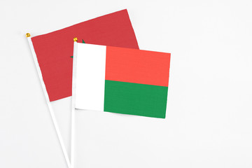 Madagascar and Morocco stick flags on white background. High quality fabric, miniature national flag. Peaceful global concept.White floor for copy space.