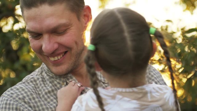 Portrait of father holding child girl in his hands and hugging each other outdoors. Dad cudding and kissing with his daughter. Father's day
