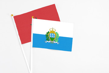 San Marino and Morocco stick flags on white background. High quality fabric, miniature national flag. Peaceful global concept.White floor for copy space.
