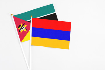 Armenia and Mozambique stick flags on white background. High quality fabric, miniature national flag. Peaceful global concept.White floor for copy space.