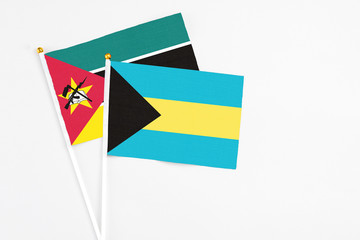 Bahamas and Mozambique stick flags on white background. High quality fabric, miniature national flag. Peaceful global concept.White floor for copy space.