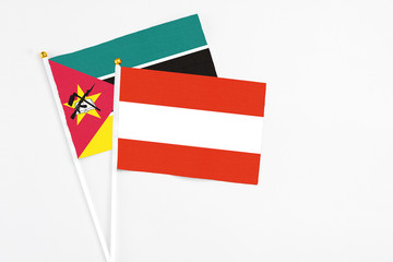 Austria and Mozambique stick flags on white background. High quality fabric, miniature national flag. Peaceful global concept.White floor for copy space.