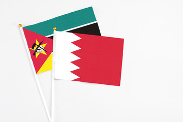 Bahrain and Mozambique stick flags on white background. High quality fabric, miniature national flag. Peaceful global concept.White floor for copy space.