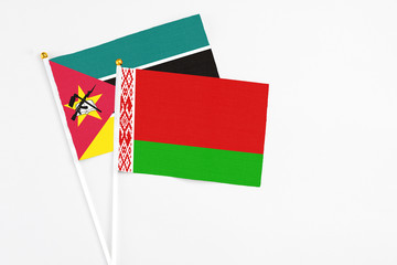 Belarus and Mozambique stick flags on white background. High quality fabric, miniature national flag. Peaceful global concept.White floor for copy space.