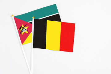 Belgium and Mozambique stick flags on white background. High quality fabric, miniature national flag. Peaceful global concept.White floor for copy space.