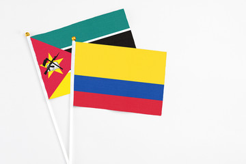 Colombia and Mozambique stick flags on white background. High quality fabric, miniature national flag. Peaceful global concept.White floor for copy space.