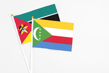 Comoros and Mozambique stick flags on white background. High quality fabric, miniature national...