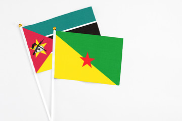 French Guiana and Mozambique stick flags on white background. High quality fabric, miniature national flag. Peaceful global concept.White floor for copy space.