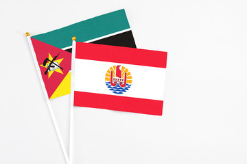 Fototapeta premium French Polynesia and Mozambique stick flags on white background. High quality fabric, miniature national flag. Peaceful global concept.White floor for copy space.