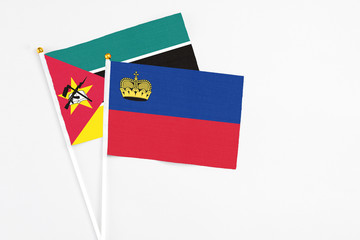 Liechtenstein and Mozambique stick flags on white background. High quality fabric, miniature national flag. Peaceful global concept.White floor for copy space.