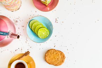 Flat lay of tea cup, cookies, lime, cinnamon and teapot. Breakfast, food and tea time concept.