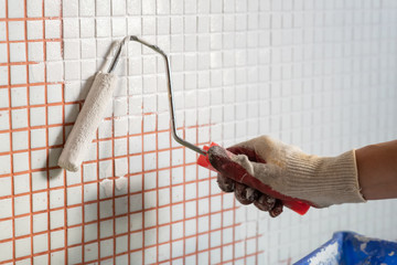 painting wall tiles with white enamel using a roller. Cheap and easy interior renovation