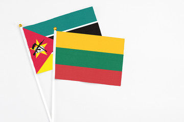Lithuania and Mozambique stick flags on white background. High quality fabric, miniature national flag. Peaceful global concept.White floor for copy space.