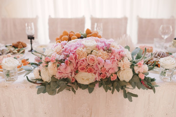 Floral arrangement of pink hydrangea, roses and eustom on the Banquet festive table of the bride and groom in pastel colors