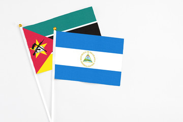 Nicaragua and Mozambique stick flags on white background. High quality fabric, miniature national flag. Peaceful global concept.White floor for copy space.
