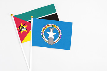 Northern Mariana Islands and Mozambique stick flags on white background. High quality fabric, miniature national flag. Peaceful global concept.White floor for copy space.