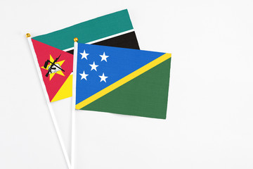 Solomon Islands and Mozambique stick flags on white background. High quality fabric, miniature national flag. Peaceful global concept.White floor for copy space.