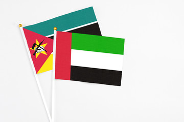 United Arab Emirates and Mozambique stick flags on white background. High quality fabric, miniature national flag. Peaceful global concept.White floor for copy space.