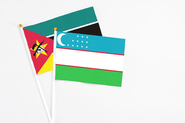 Uzbekistan and Mozambique stick flags on white background. High quality fabric, miniature national flag. Peaceful global concept.White floor for copy space.