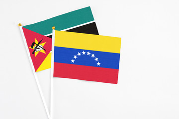 Venezuela and Mozambique stick flags on white background. High quality fabric, miniature national flag. Peaceful global concept.White floor for copy space.