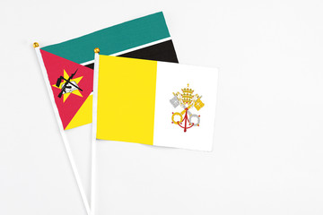Vatican City and Mozambique stick flags on white background. High quality fabric, miniature national flag. Peaceful global concept.White floor for copy space.