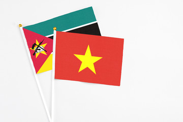 Vietnam and Mozambique stick flags on white background. High quality fabric, miniature national flag. Peaceful global concept.White floor for copy space.