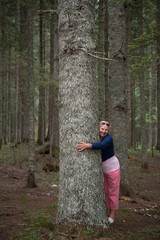 Woman is hugging tree trunk in national park Durmitor,