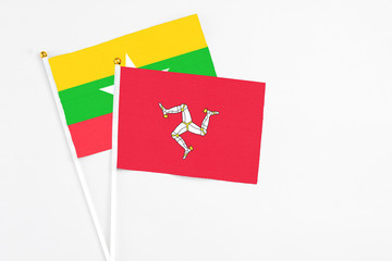 Isle Of Man and Myanmar stick flags on white background. High quality fabric, miniature national flag. Peaceful global concept.White floor for copy space.