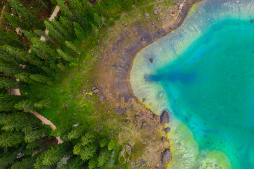 Aerial view of turquoise blue water of lake Carezza in Alps Dolomites. Lago di Karersee near fir tree forest.