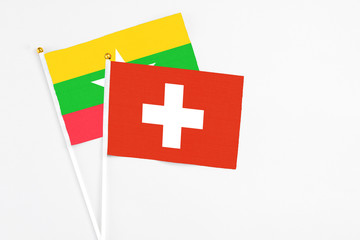 Switzerland and Myanmar stick flags on white background. High quality fabric, miniature national flag. Peaceful global concept.White floor for copy space.