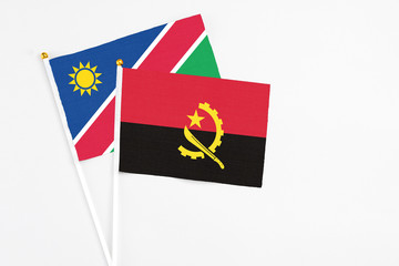Angola and Namibia stick flags on white background. High quality fabric, miniature national flag. Peaceful global concept.White floor for copy space.