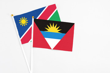 Antigua and Barbuda and Namibia stick flags on white background. High quality fabric, miniature national flag. Peaceful global concept.White floor for copy space.