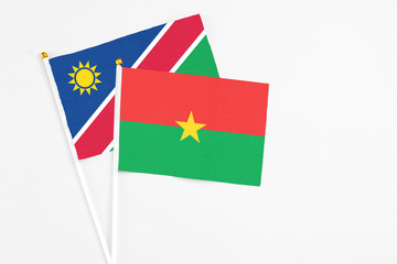 Burkina Faso and Namibia stick flags on white background. High quality fabric, miniature national flag. Peaceful global concept.White floor for copy space.