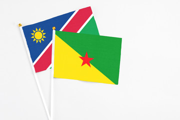 French Guiana and Namibia stick flags on white background. High quality fabric, miniature national flag. Peaceful global concept.White floor for copy space.