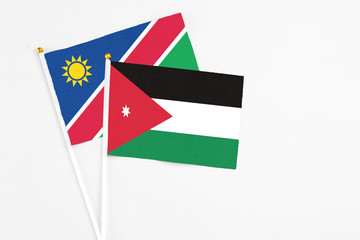 Jordan and Namibia stick flags on white background. High quality fabric, miniature national flag. Peaceful global concept.White floor for copy space.