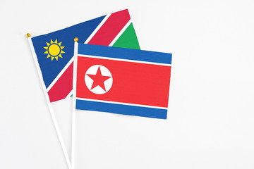 North Korea and Namibia stick flags on white background. High quality fabric, miniature national flag. Peaceful global concept.White floor for copy space.
