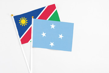 Micronesia and Namibia stick flags on white background. High quality fabric, miniature national flag. Peaceful global concept.White floor for copy space.