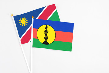 New Caledonia and Namibia stick flags on white background. High quality fabric, miniature national flag. Peaceful global concept.White floor for copy space.