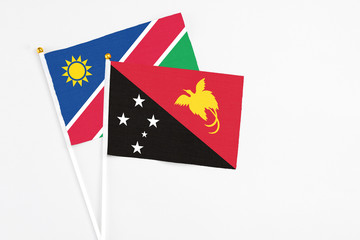 Papua New Guinea and Namibia stick flags on white background. High quality fabric, miniature national flag. Peaceful global concept.White floor for copy space.