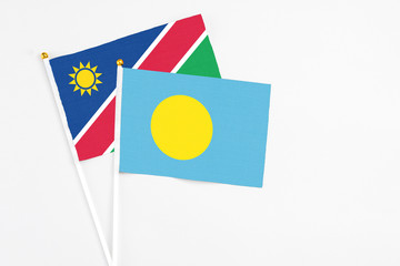 Palau and Namibia stick flags on white background. High quality fabric, miniature national flag. Peaceful global concept.White floor for copy space.