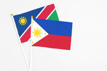 Philippines and Namibia stick flags on white background. High quality fabric, miniature national flag. Peaceful global concept.White floor for copy space.