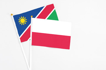 Poland and Namibia stick flags on white background. High quality fabric, miniature national flag. Peaceful global concept.White floor for copy space.