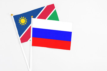 Obraz premium Russia and Namibia stick flags on white background. High quality fabric, miniature national flag. Peaceful global concept.White floor for copy space.